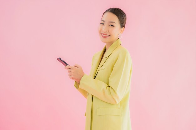 Portret piękna młoda azjatycka biznesowa kobieta używa inteligentnego telefonu komórkowego z filiżanką kawy na kolor