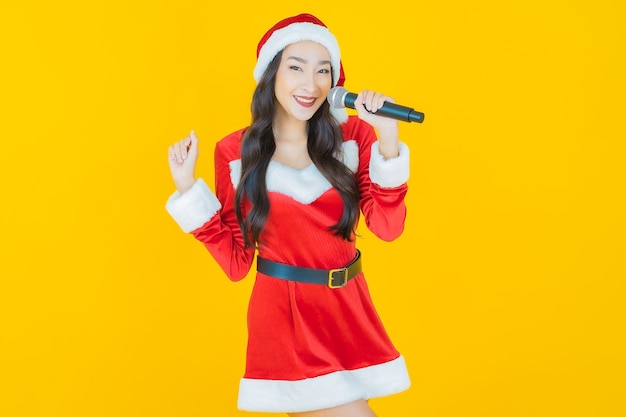 Portret piękna młoda azjatycka kobieta nosi świąteczny kostium z mikrofonem do śpiewania na żółto