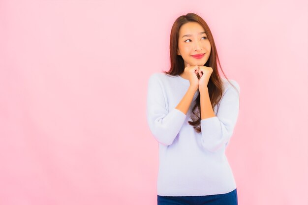Portret piękna młoda azjatycka kobieta uśmiech z działaniem na różowej ścianie na białym tle