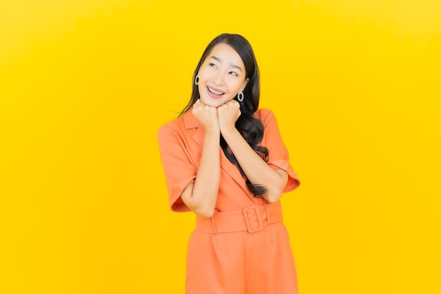 Portret piękna młoda azjatycka kobieta uśmiech z działaniem na żółto