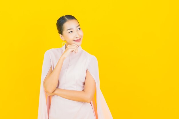 Portret piękna młoda azjatycka kobieta uśmiech z wieloma działaniami na żółtej ścianie