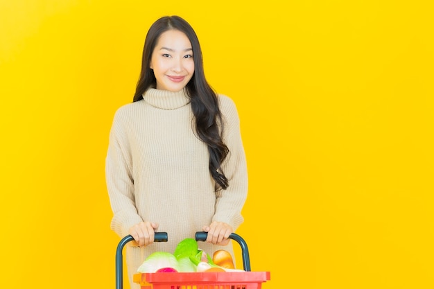 Portret Piękna Młoda Azjatycka Kobieta Uśmiecha Się Z Koszem Spożywczym Z Supermarketu Na żółtej ścianie
