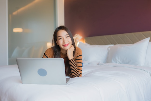 Portret piękna młoda azjatycka kobieta używa laptopa na łóżku