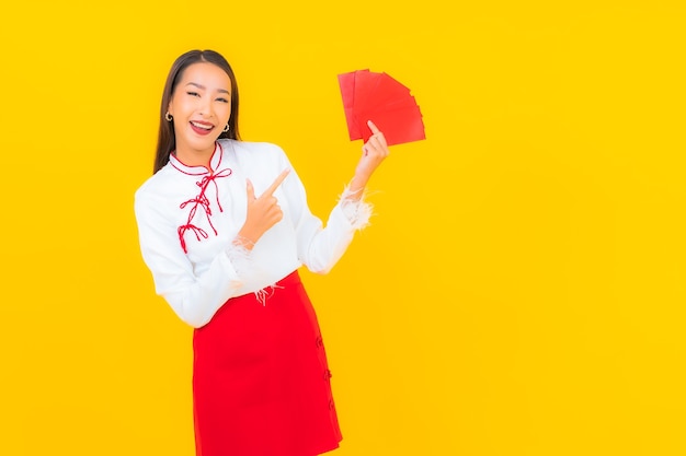 Portret piękna młoda azjatycka kobieta z czerwonymi kopertami list w chińskim nowym roku na żółto