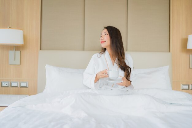 Portret piękna młoda azjatycka kobieta z inteligentny telefon komórkowy w sypialni