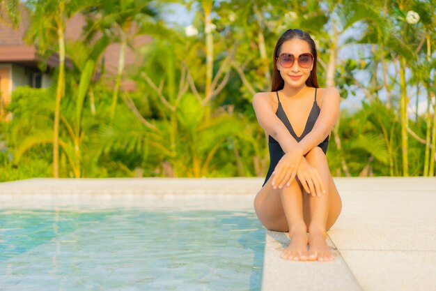 Portret piękna młoda azjatykcia kobieta relaksuje się wokół basenu w hotelu na wakacjach