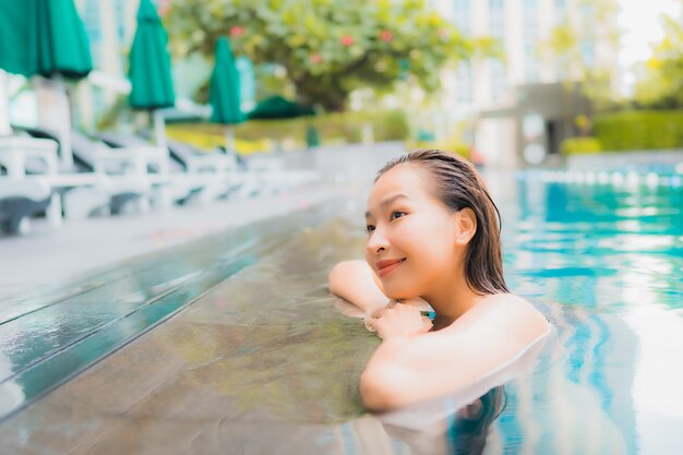Portret piękna młoda azjatykcia kobieta relaksuje szczęśliwego uśmiechu czas wolnego wokoło plenerowego pływackiego basenu