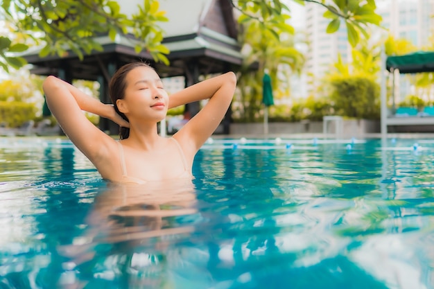 Portret piękna młoda azjatykcia kobieta relaksuje szczęśliwego uśmiechu czas wolnego wokoło plenerowego pływackiego basenu