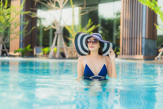 Portret piękna młoda azjatykcia kobieta relaksuje w pływackim basenie w hotelowym kurorcie