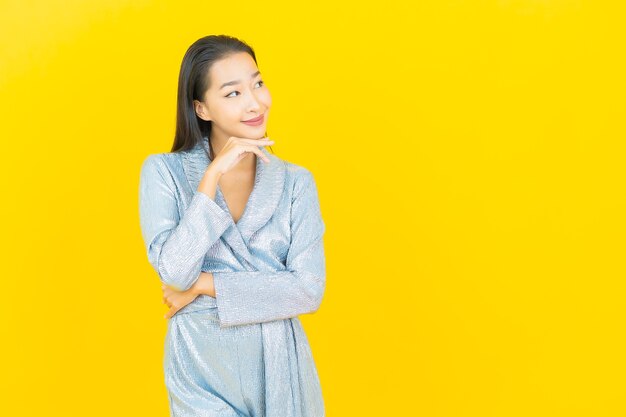 Portret piękna młoda azjatykcia kobieta uśmiech z działaniem na żółtej ścianie