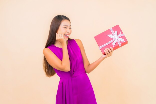 Portret piękna młoda azjatykcia kobieta z czerwonym pudełkiem na kolor na białym tle