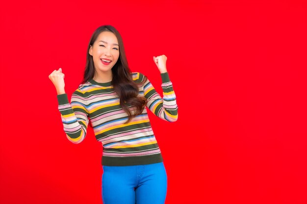 Portret piękna młoda kobieta azjatyckich uśmiech z działaniem na czerwonej ścianie na białym tle