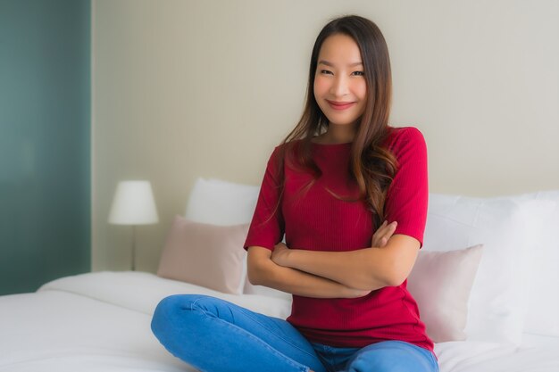 Portret piękne młode azjatykcie kobiety uśmiechają się szczęśliwego na łóżku