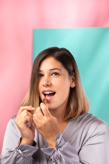 Portret pięknej kobiety nakładającej szminkę na usta