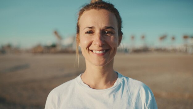 Portret pięknej kobiety patrzącej w kamerę i uśmiechającej się spędzającej czas na plaży Młoda sportowa kobieta pozuje na zewnątrz