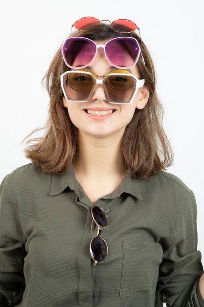 Portret pięknej kobiety sobie wiele okularów przeciwsłonecznych na białym. Zdjęcie wysokiej jakości