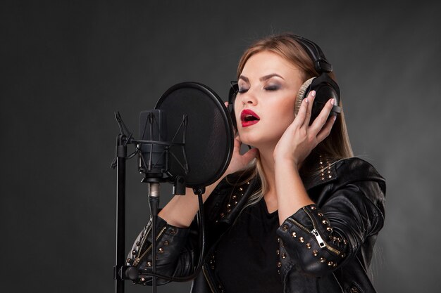 Portret pięknej kobiety śpiewającej do mikrofonu ze słuchawkami