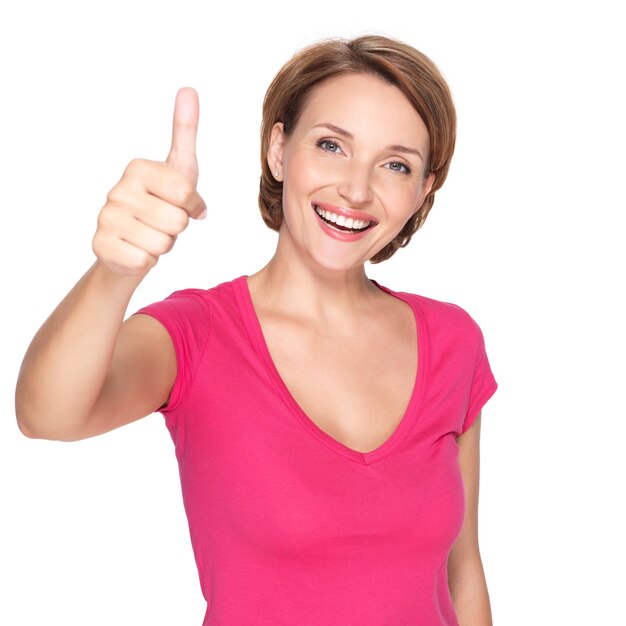 Portret pięknej kobiety szczęśliwy dorosłych z kciuki do góry znak na białej ścianie