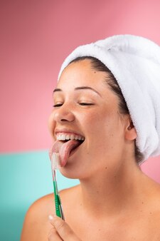 Portret pięknej kobiety używającej szczoteczki do zębów do czyszczenia języka