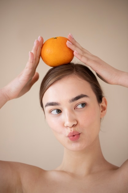 Bezpłatne zdjęcie portret pięknej kobiety z czystą skórą trzymającą pomarańczowe owoce