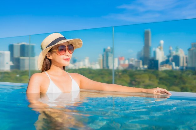 Portret pięknej młodej azjatyckiej kobiety uśmiech relaksujący wypoczynek wokół odkrytego basenu z widokiem na miasto