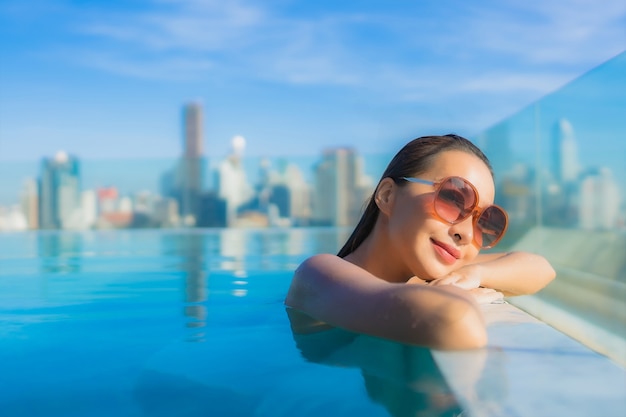 Portret pięknej młodej azjatyckiej kobiety uśmiech relaksujący wypoczynek wokół odkrytego basenu z widokiem na miasto