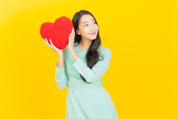 Portret pięknej młodej azjatyckiej kobiety uśmiech w kształcie poduszki w kształcie serca na żółto