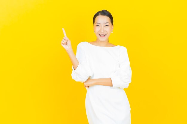 Portret pięknej młodej azjatyckiej kobiety uśmiech z akcją na żółto