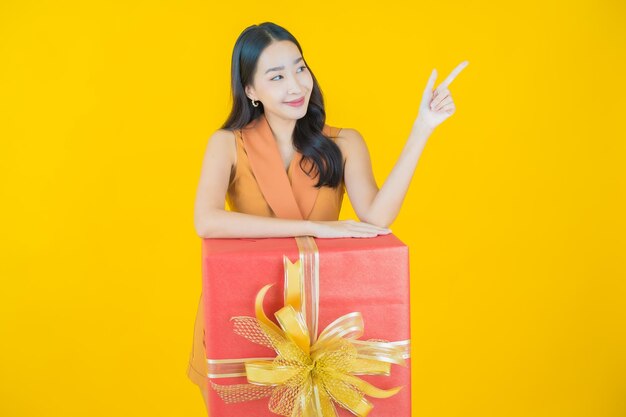 Portret pięknej młodej azjatyckiej kobiety uśmiech z czerwonym pudełkiem na prezent
