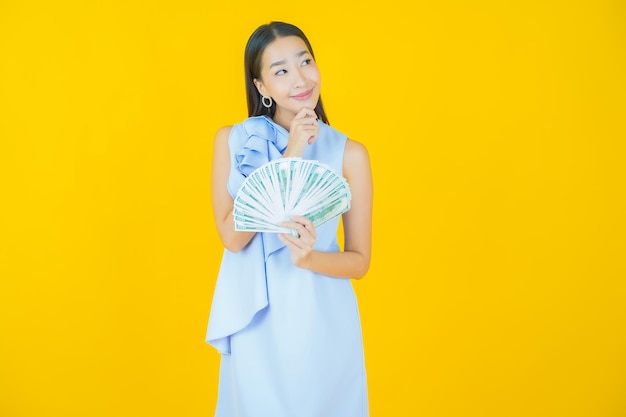 Portret pięknej młodej azjatyckiej kobiety uśmiech z dużą ilością gotówki i pieniędzy na żółto