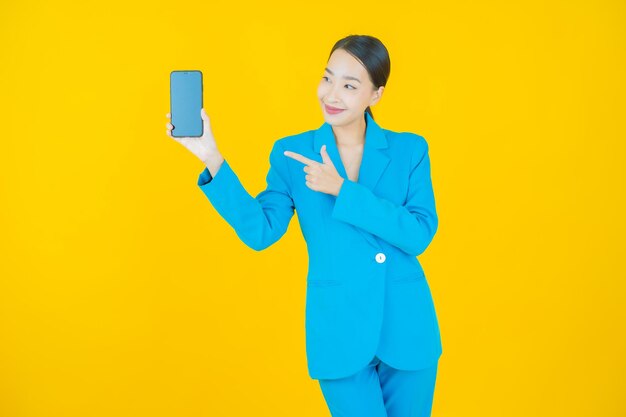 Portret pięknej młodej azjatyckiej kobiety uśmiech z inteligentnym telefonem komórkowym na żółto