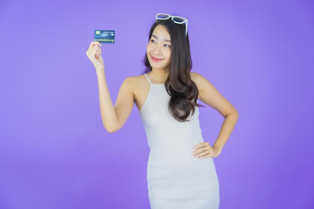 Portret pięknej młodej azjatyckiej kobiety uśmiech z kartą kredytową na kolorowym tle
