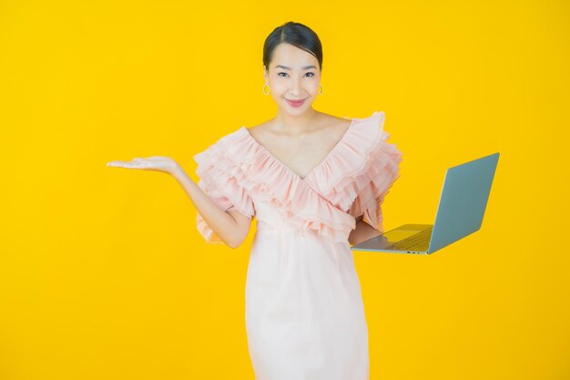 Portret pięknej młodej azjatyckiej kobiety uśmiech z laptopem na żółto