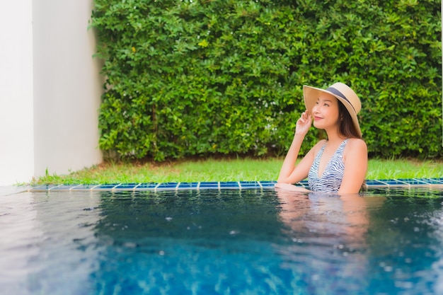 Portret pięknej młodej azjatykciej kobiety szczęśliwy uśmiech relaksuje wokoło plenerowego pływackiego basenu w hotelowym kurorcie