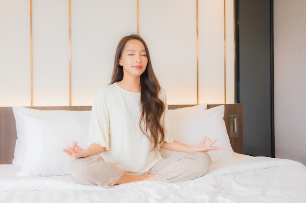 Portret pięknej młodej kobiety azjatyckie medytacji na łóżku we wnętrzu sypialni
