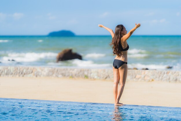 Portret pięknej młodej kobiety azjatyckie nosić bikini wokół basenu w hotelowym kurorcie prawie oceanu morza plaży