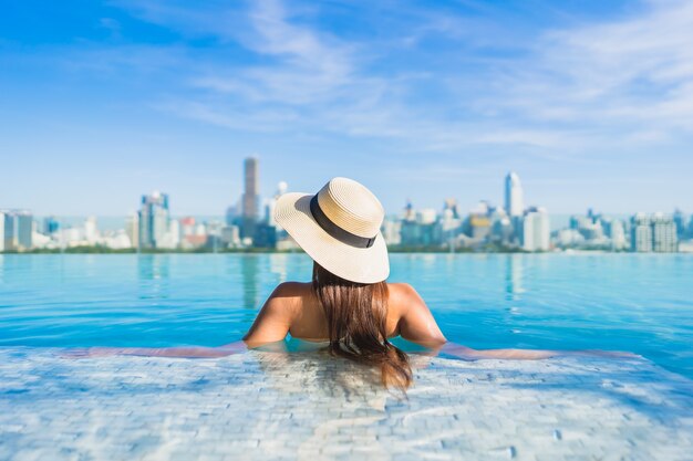 Portret pięknej młodej kobiety azjatyckie relaks przy odkrytym basenie z widokiem na miasto