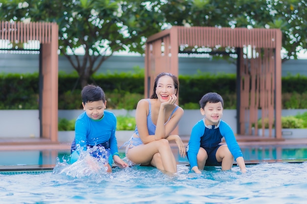 Portret pięknej młodej kobiety azjatyckiej cieszyć się szczęśliwym relaksem z synem przy basenie