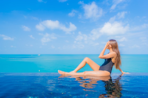Portret pięknej młodej kobiety azjatyckiej relaks uśmiech wypoczynek wokół odkrytego basenu w hotelu z widokiem na morze