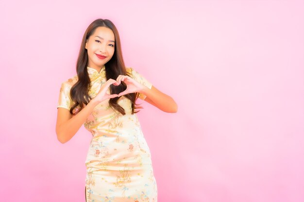 Portret pięknej młodej kobiety azjatyckiej uśmiech w akcji z koncepcją chińskiego nowego roku na różowej ścianie