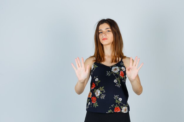 Portret pięknej młodej kobiety pokazano gest stop w bluzce
