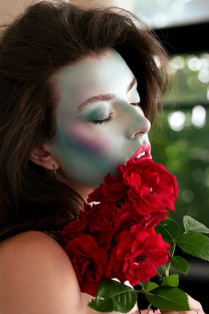 Portret pięknej młodej kobiety z farbą do twarzy i kwiatami