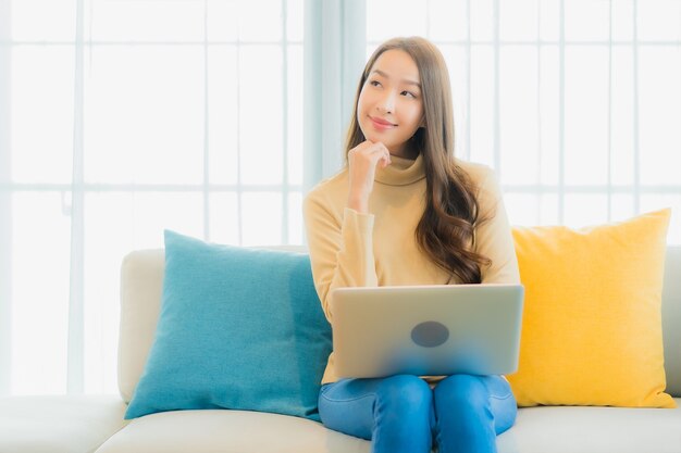 Portret pięknej młodej kobiety za pomocą laptopa na kanapie w salonie