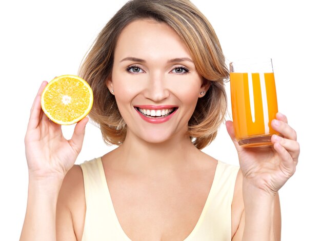 Portret pięknej młodej kobiety ze szklanką soku i pomarańczy na białym tle.