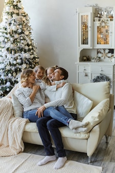 Portret pięknej szczęśliwej rodziny z dwójką dzieci w białych swetrach