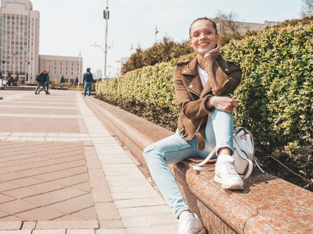 Portret piękny uśmiechnięty brunetka model ubierał w lato modnisia kurtce i cajgach odziewa