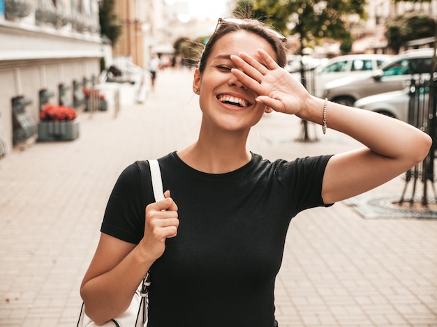 Portret piękny uśmiechnięty model ubierający w lecie odziewa. Modna dziewczyna pozuje na ulicy. Śmieszna i pozytywna kobieta ma zabawę