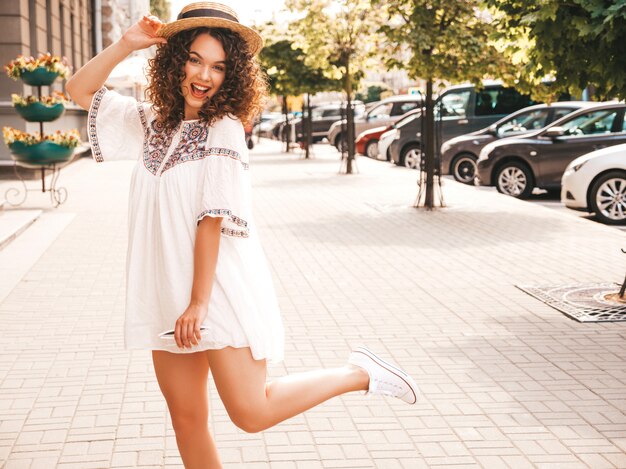 Portret piękny uśmiechnięty model z fryzurą afro loki ubrany w letnią białą sukienkę hipster.