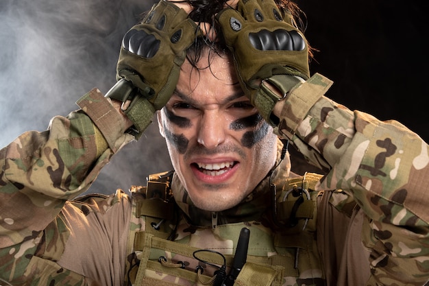 Portret płaczącego młodego żołnierza w kamuflażu na czarnej ścianie