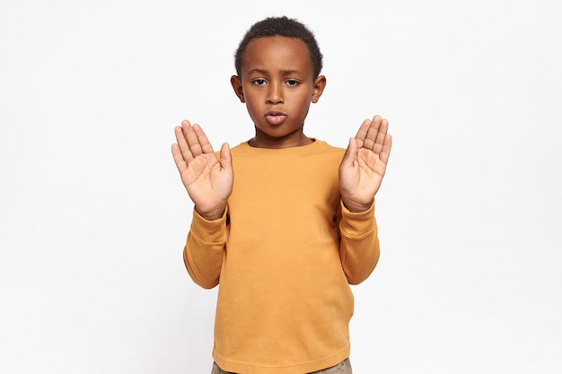 Portret poważnego pewnie African American ucznia w bluzie wyciągając ręce z otwartymi dłońmi, wykonując gest stopu